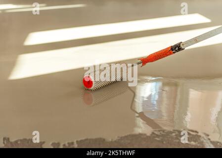 Needle roller for self-leveling floors. Leveling the floors with a cement mixture. Stock Photo