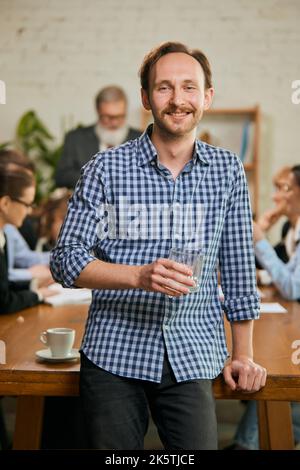 Senior developer. Happy man looking at camera and smilling. Work in modern loft style office using devices and gadgets during job processing. Stock Photo