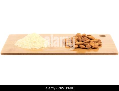 Heaps of almond flour and almond kernels on a cutting board isolated on white background. Copy space. Stock Photo
