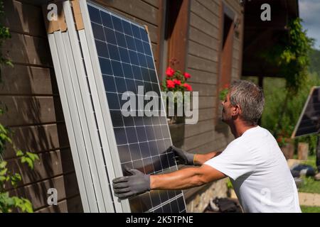 Mature man worker carrying solar panel for installing. Stock Photo