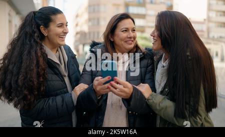 Mother and daugthers using smartphone standing together at street Stock Photo