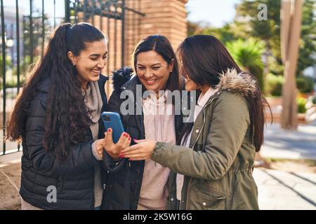 Three woman mother and daughters using smartphone at street Stock Photo