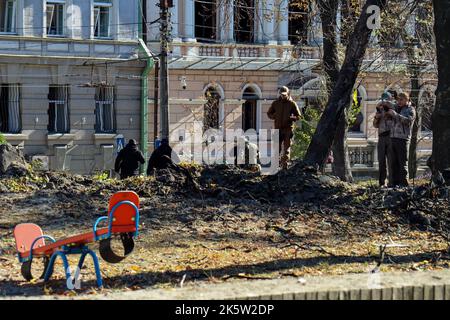 Kiew, Ukraine. 10th Oct, 2022. People stand on a damaged children's playground. After Russian missile attacks, the air alert in the Ukrainian capital Kiev was lifted after more than five and a half hours. A reporter for Deutsche Presse-Agentur in the center of the metropolis reported Monday that people were leaving basements and pedestrians could be seen on the streets again. Credit: Hannah Wagner/dpa/Alamy Live News Stock Photo