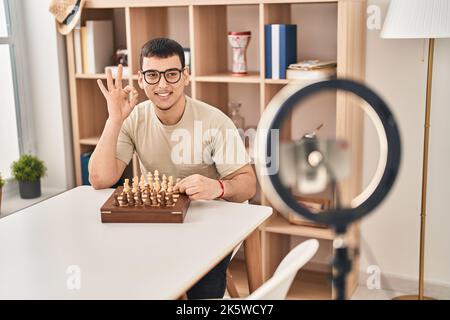 Young arab man doing chess tutorial doing ok sign with fingers, smiling friendly gesturing excellent symbol Stock Photo