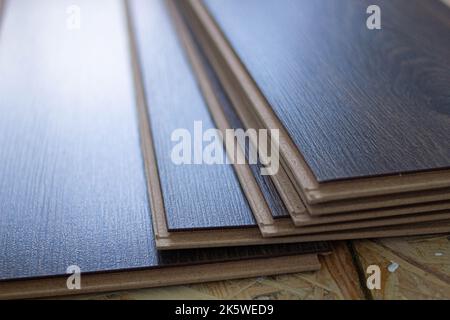 Laminate. Laying brown glossy laminate on the floor of the house. Apartment renovation. Replacing old floor with a new one. Laminate sheets are placed Stock Photo