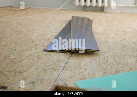 Laminate. Laying brown glossy laminate on the floor of the house. Apartment renovation. Replacing old floor with a new one. Laminate sheets are placed Stock Photo