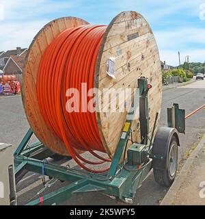 Cable drum wooden timber sides mounted on towable trailer new fibre optic broadband infrastructure supply for residential village properties Essex UK Stock Photo