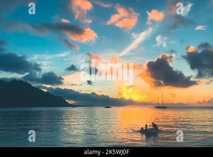 Multi colored tropic sunset over calm sea water. Yacht boats silhouette against blue orange clouds in sky, mountain in background. Beautiful nature landscape. Travel, tourism, holiday destination Stock Photo