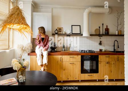 Modern kitchen interior with person sitting on table top Stock Photo