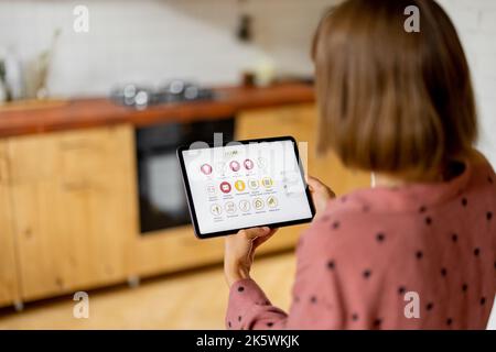 Woman controls home devices with a digital tablet at home Stock Photo