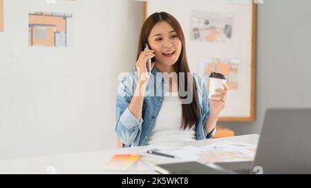 Design building concept, Female architect talks on smartphone while relax from sketching house plan. Stock Photo