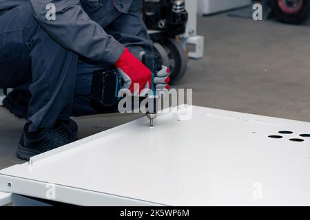 assembly of a metal structure in the workshop using a screwdriver Stock Photo