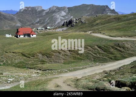 Chalet Real and Hotel Aliva against the backdrop of the Eastern Massif, Picos de Europa, northern Spain. A path sweeps through to the far distance. Stock Photo