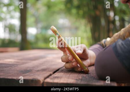 women hand holding smart phone on table in nature  Stock Photo