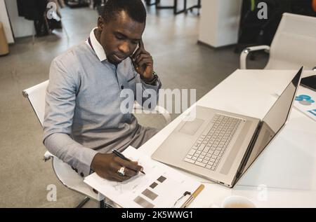A black African American businessman in a business suit works at a laptop. Analytics and work online Stock Photo