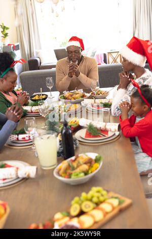 Vertical picture of african american family praying before having christmas meal Stock Photo
