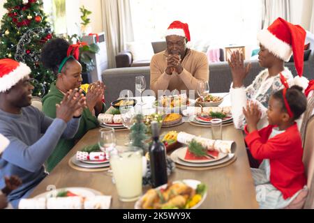 African american family spending time together and praying before having christmas meal Stock Photo