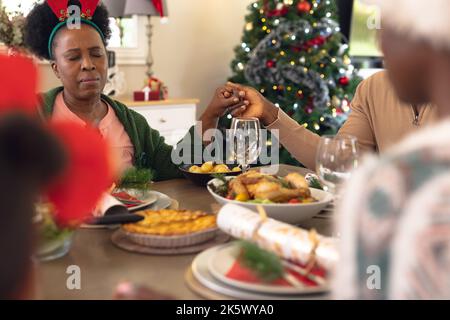Happy african american family praying before having christmas meal Stock Photo