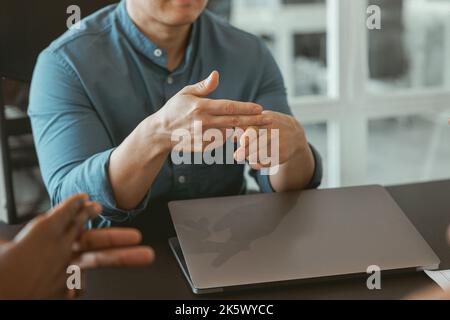 Close up of businessman using sign language while talking with client sitting in office Stock Photo