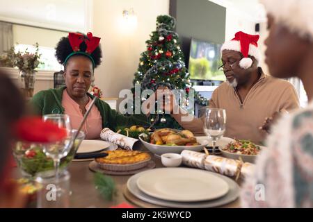 Happy african american family praying before having christmas meal Stock Photo