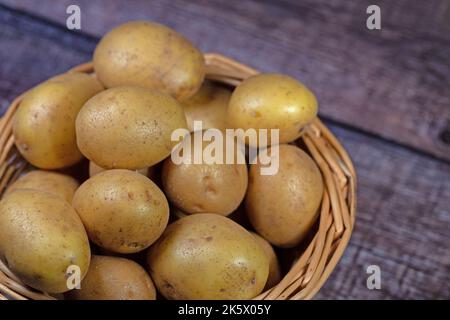 Potatoes in the basket on wooden background Stock Photo