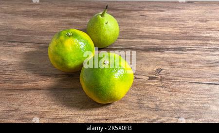 Two oranges and one pear on a wooden table. Stock Photo