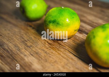 A selective focus of an orange on a wooden table with a green pear in the background. Stock Photo