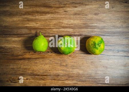 A top view of two oranges and one pear on a wooden table. Stock Photo