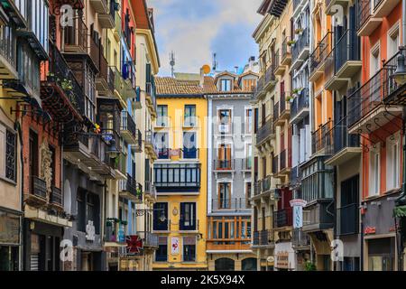 Pamplona, Spain - June 21, 2021: Colorful houses with flowers on ornate metal balconies in the old town or Casco Viejo Pamplona, famous for bull runs Stock Photo