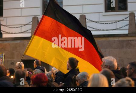 Schwerin, Germany. 10th Oct, 2022. Participants start a demonstration against the energy policy in the Northeast, one demonstrator carries a large German flag. Credit: Bernd Wüstneck/dpa/Alamy Live News Stock Photo