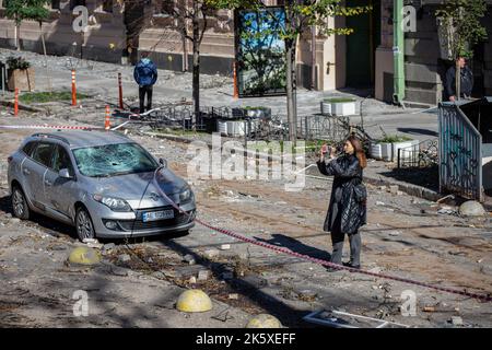 Kyiv, Ukraine. 10th Oct, 2022. A girl takes pictures near the damaged car after a Russian missile attack in central Kyiv. Explosions have been reported in several districts of the Ukrainian capital Kyiv on October 10, 2022. At least 11 people died and dozens injured as a result of Russian rocket attacks targeting cities across Ukraine. (Photo by Oleksii Chumachenko/SOPA Images/Sipa USA) Credit: Sipa USA/Ģ����ý Live News Stock Photo