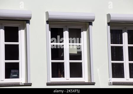 New muntin windows with front-mounted roller shutters on a renovated old building Stock Photo