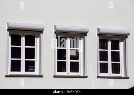 New muntin windows with front-mounted roller shutters on a renovated old building Stock Photo