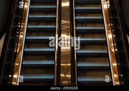 Escalators in the modern building. Golden and gray colored escalators background photo. Architecture concept. Stock Photo