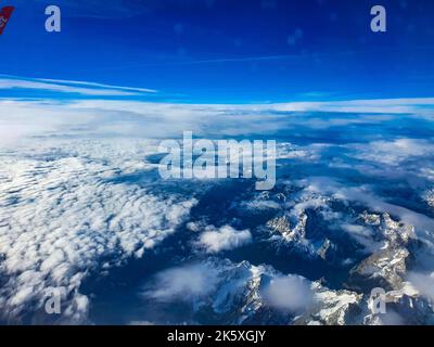 The Alps from the plane with a scattering of snow and cloud Stock Photo ...