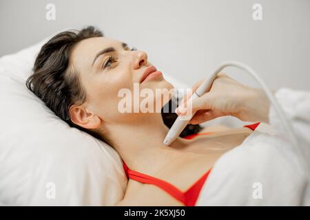 Woman examining thyroid gland with ultrasound Stock Photo