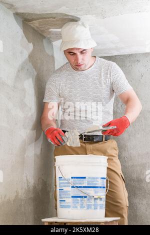 Dolyna , Ukraine April 11, 2022:The master works with lime plaster, leveling the wall with a spatula and lime plaster, repairing work on leveling the Stock Photo