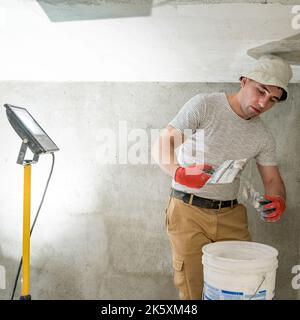 The master works with lime plaster, leveling the wall with a spatula and lime plaster, repairing work on leveling the walls. Stock Photo