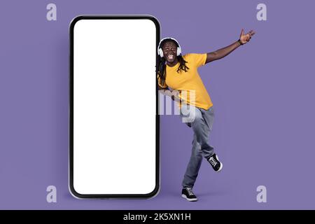Happy black guy listening to muisc, using wireless headset Stock Photo