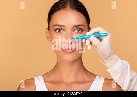 Rhinoplasty concept. Doctor making marks on patient's face, young caucasian lady on consultation at surgeon Stock Photo