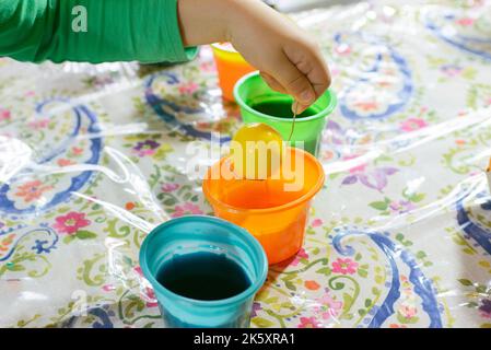 Child coloring Easter Egg with Yellow Dye Stock Photo