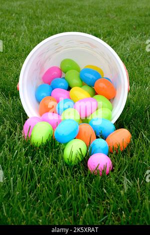 Colorful Plastic Easter Eggs spilling out of Bucket on Green Grass Stock Photo