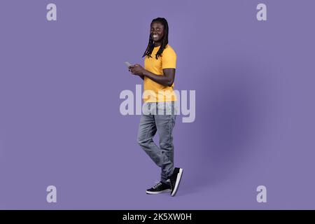 Cool african american guy using cell phone on purple Stock Photo