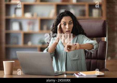 Stressed young businesswoman looking at watch, got late Stock Photo