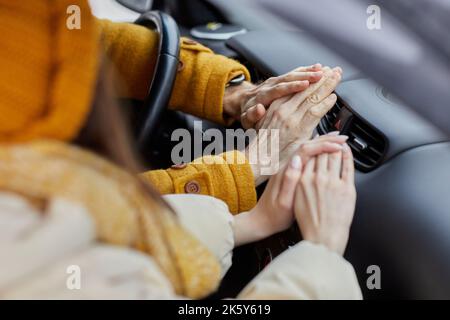 Close up of freezing young couple trying to warm hands on car heater, travelling in winter Stock Photo