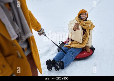 High angle view at young couple sledding downhill while enjoying fun winter activities together Stock Photo