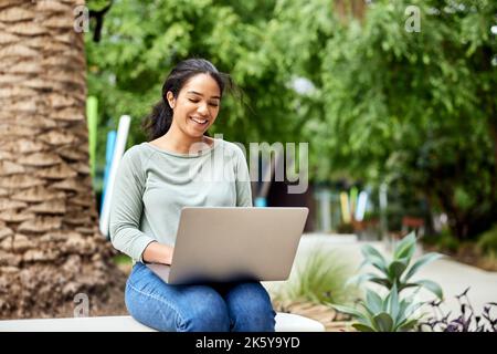 Smiling female freelancer using laptop while sitting on bench Stock Photo