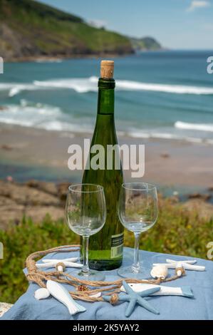 Tasting of txakoli or chacolí slightly sparkling very dry white wine produced in Spanish Basque Country, served outdoor with view on Bay of Biscay, At Stock Photo