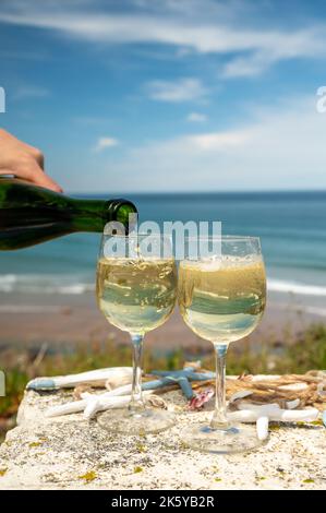 Tasting of txakoli or chacolí slightly sparkling very dry white wine produced in Spanish Basque Country, served outdoor with view on Bay of Biscay, At Stock Photo