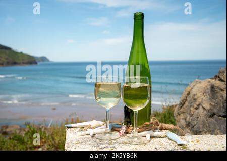 Tasting of txakoli or chacolí slightly sparkling very dry white wine produced in Spanish Basque Country, served outdoor with view on Bay of Biscay, At Stock Photo